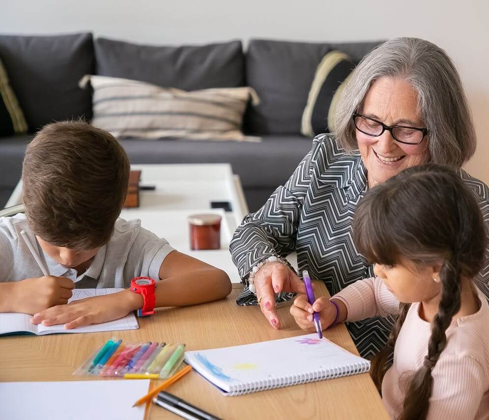 An older woman helps children with coloring